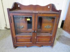 A VINTAGE WOODEN SMOKERS CABINET WITH GLAZED DOORS