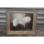 A SMALL GILT FRAMED OIL ON BOARD OF A PONY IN A STABLE