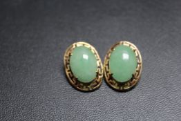 A PAIR OF UNMARKED YELLOW METAL EARRINGS SET WITH CABOCHON POLISHED GREEN STONES, with clip on faste