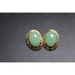 A PAIR OF UNMARKED YELLOW METAL EARRINGS SET WITH CABOCHON POLISHED GREEN STONES, with clip on faste