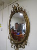 A 19TH CENTURY LARGE GILT OVAL WALL MIRROR WITH TWIN CANDLE SCONCE, having a scrolling foliate