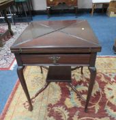 AN EDWARDIAN MAHOGANY ENVELOPE GAMES TABLE, the leaves opening to a baize lined interior, with