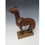 AN EARLY 20TH CENTURY NAIVE WOODEN CARVING OF A HORSE, on a rectangular wooden plinth, Overall H