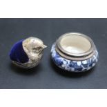 A SMALL CHICK PIN CUSHION TOGETHER WITH A SILVER RIMMED SALT DISH, (2)