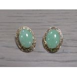 A PAIR OF UNMARKED YELLOW METAL EARRINGS SET WITH CABOCHON POLISHED GREEN STONES, with clip on