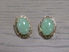A PAIR OF UNMARKED YELLOW METAL EARRINGS SET WITH CABOCHON POLISHED GREEN STONES, with clip on