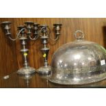 AN ENGRAVED SILVER PLATED FOOD DOME TOGETHER WITH A PAIR OF PLATED CANDELABRA