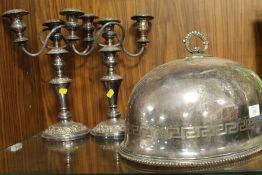 AN ENGRAVED SILVER PLATED FOOD DOME TOGETHER WITH A PAIR OF PLATED CANDELABRA