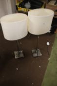 A PAIR OF STAINLESS STEEL TABLE LAMPS WITH MATCHING CREAM SHADES