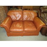 A SMALL BROWN LEATHER TWO SEATER SETTEE