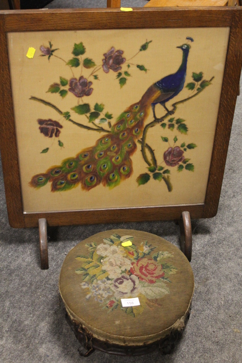 A VINTAGE OAK FIRESCREEN WITH PEACOCK DESIGN TOGETHER WITH A CARVED TAPESTRY TOP MAHOGANY FOOT