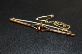 A 9CT BAR BROOCH SET WITH CENTRAL RED STONE
