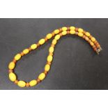 A NECKLACE THREADED WITH GRADUATING ALTERNATING AMBER AND BUTTERSCOTCH STYLE BEADS