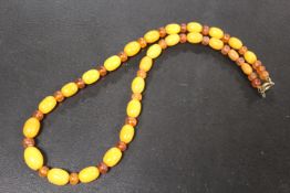 A NECKLACE THREADED WITH GRADUATING ALTERNATING AMBER AND BUTTERSCOTCH STYLE BEADS