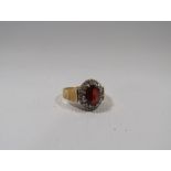 A VINTAGE 18CT GOLD LADIES GEMSET DRESS RING, the central oval faceted red stone surrounded by small