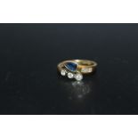 AN UNUSUAL HALLMARKED 18 CARAT GOLD SAPPHIRE AND DIAMOND RING, in a crossover style with a