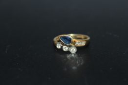AN UNUSUAL HALLMARKED 18 CARAT GOLD SAPPHIRE AND DIAMOND RING, in a crossover style with a
