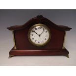 AN EDWARDIAN MAHOGANY CASED MANTLE CLOCK, the case having shaped surmount and brass pillars, the