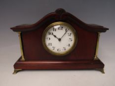 AN EDWARDIAN MAHOGANY CASED MANTLE CLOCK, the case having shaped surmount and brass pillars, the