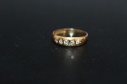 A HALLMARKED 18 CARAT GOLD DIAMOND SET BAND, having 5 diamonds totaling an estimated 0.12 carat,