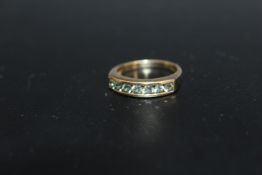 A HALLMARKED 9 CARAT GOLD GEM SET RING, having brilliant cut alexandrite style stones in a channel