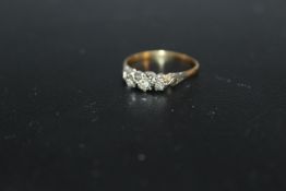 A THREE STONE DIAMOND RING, in an illusion setting with small diamond accents, marks extremely