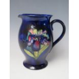 A MOORCROFT POTTERY IRIS PATTERN JUG, of baluster form, on a blue ground, signature and painted