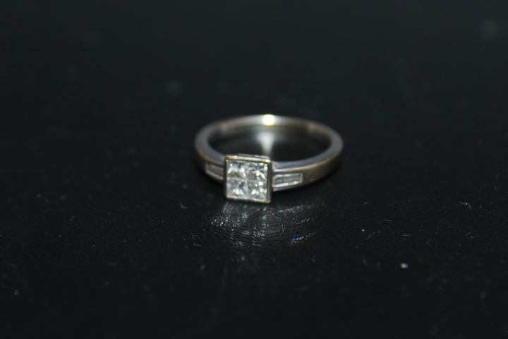 A SIX STONE DIAMOND RING, having four Princess cut diamonds set in a square...
