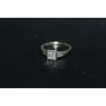 A SIX STONE DIAMOND RING, having four Princess cut diamonds set in a square in a rub over setting