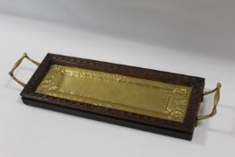 AN UNUSUAL OAK FRAMED ARTS AND CRAFTS BRASS RECTANGULAR TRAY, having twin handles, the tray with