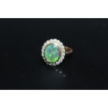 A HALLMARKED 18 CARAT GOLD OPAL AND DIAMOND RING, the central oval opal being of an estimated 2.33