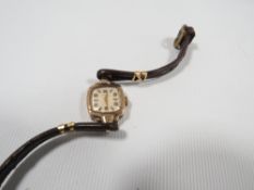 A 9CT GOLD CASED AVIA WRISTWATCH, on leather strap with gilt metal mounts