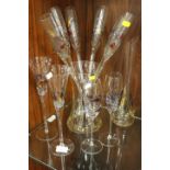 A COLLECTION OF ART GLASS DRINKING FLUTES IN A VASE , WINE GLASSES AND A CARAFE