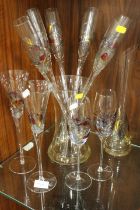 A COLLECTION OF ART GLASS DRINKING FLUTES IN A VASE , WINE GLASSES AND A CARAFE