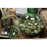 A TRAY OF GLASSWARE TO INCLUDE LARGE GREEN VESSEL FILLED WITH PEBBLES AND GLASS BEADS