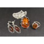 AN AMBER PENDANT OF SILVER CHAIN TOGETHER WITH A RING AND EARRINGS