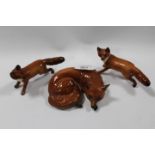 A BESWICK CURLED UP FOX TOGETHER WITH TWO SMALL RUNNING FOXES