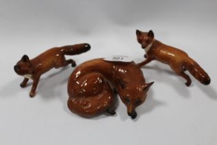 A BESWICK CURLED UP FOX TOGETHER WITH TWO SMALL RUNNING FOXES