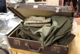 A VINTAGE LEATHER SUITCASE CONTAINING ARMY CLOTHING, CANVAS BAGS ETC
