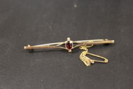 A 9CT BAR BROOCH SET WITH CENTRAL RED STONE