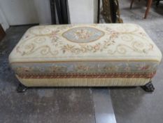 A VINTAGE LARGE NEEDLEPOINT FOOT STOOL WITH LION PAW FEET 130CM