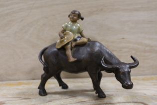 AN ORIENTAL CERAMIC FIGURE OF A YOUNG GIRL SEATED ON A WATER BUFFALO