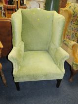 A LARGE GREEN UPHOLSTERED WING ARMCHAIR