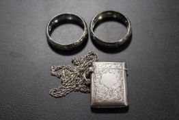 AN ANTIQUE SILVER VESTA CASE ON SILVER CHAIN TOGETHER WITH TWO NAPKIN RINGS