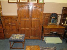 AN OAK LINENFOLD BEDROOM SUITE COMPRISING DOUBLE WARDROBE, TALLBOY, DRESSING TABLE, MIRROR, STOOL