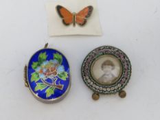 A MINIATURE CIRCULAR MICRO MOSAIC PICTURE FRAME, together with an enamelled butterfly brooch and a