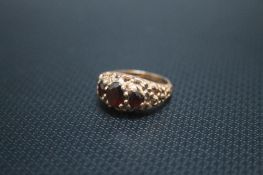 A 9CT GOLD THREE STONE GARNET RING IN RAISED PIERCED GALLERY SETTING, approx weight 4.3g, ring