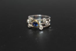 A HANDMADE 18 CARAT WHITE GOLD SAPPHIRE AND DIAMOND SPLIT BAND RING, set with a single sapphire of