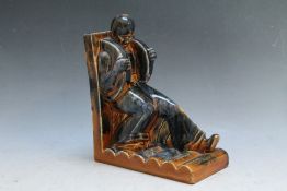 A INDUSTRIALIST STYLE CERAMIC BOOKEND IN THE FORM A WORKMAN PUSHING IN A HARNESS AND CLOGGS, in a