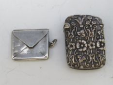 A VINTAGE ORNATE WHITE METAL VESTA CASE, together with a hallmarked silver envelope stamp case, 2